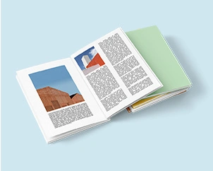 Opened A4 photo book with architectural images on a stack of books